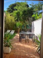 a patio with a table and chairs and palm trees at Maisonette avec jardinet sur le bas du Faron in Toulon