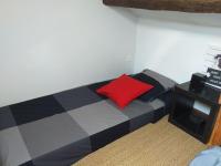 a bed with a red pillow in a room at Maisonette avec jardinet sur le bas du Faron in Toulon
