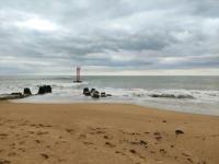 a sandy beach with a lighthouse in the ocean at Gîte Ty Maen à Plouhinec (56) 4 in Plouhinec