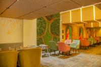 a restaurant with tables and chairs and a wall with trees at Amritara Maa Katra in Katra