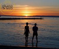 a man and woman standing on the beach watching the sunset at Les Pieds dans le Sable in Le Grau-du-Roi