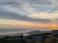 un tramonto su una spiaggia con una città e l'oceano di DAN EN WAN a Oesterbaai