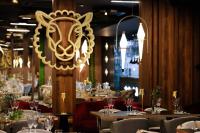 ein Esszimmer mit Tischen und einem Löwenkopf-Kronleuchter in der Unterkunft Domki Osada Bacówka Radawa & SPA in Radawa