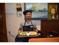 Ein Mann, der ein Tablett mit einem Teller Essen hält. in der Unterkunft The Revett in Darjeeling