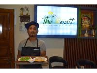 Ein Mann, der ein Tablett mit einem Teller Essen hält. in der Unterkunft The Revett in Darjeeling