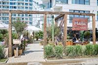 un giardino con pergolato in legno di fronte a un edificio di Sandy Breeze - Jacuzzi & Sauna Infinity Resort a Mamaia Nord - Năvodari