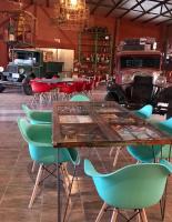 Una mesa y sillas en una habitación con un camión viejo. en Posada de campo Mamúll Mapú, en Rancul