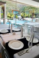 Una mesa con platos blancos y cubiertos de plata y una piscina. en Maloka Hotel Boutique & Spa, en Playa Guacuco
