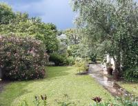 a garden with trees and pink flowers and grass at Studio Les Oliviers in Noisy-le-Grand