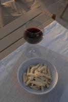 a plate of pasta next to a glass of wine at AlaBora Hotel in Alacati