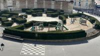 a courtyard with green hedges and a table and chairs at Amazing view on the Versailles Palace - Paris 15min in Versailles