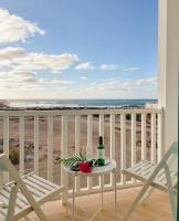 a table with a bottle of wine on a balcony with the beach at Papaya Apartments Boa Vista in Sal Rei