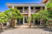 a house with a balcony and trees in front of it at Southern Sun Homestay North in Kenting