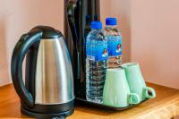 a coffee pot with two bottles of water and two cups at Southern Sun Homestay North in Kenting