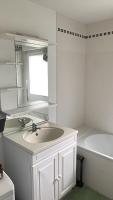a white bathroom with a sink and a tub at Appartement lumineux de 60m2 in Guer