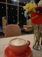 a cup of coffee on a table with a vase of flowers at The Clover Hotel Angeles City in Angeles
