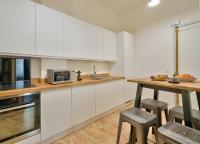 a kitchen with white cabinets and a table with stools at GuestReady - Beautiful Apt near Paris Zoo in Paris