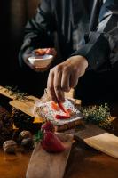 ビジャ・ヘネラル・ベルグラーノにあるCalina Casa de Huéspedesのテーブルの上で果物が入ったパンを切っている人