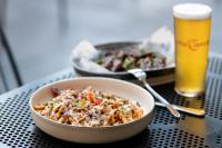 a bowl of pasta on a table with two glasses of beer at Mercure Perth On Hay in Perth