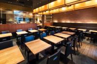 大分市にあるホテルマイステイズ大分の木製のテーブルと椅子が置かれた空のレストラン