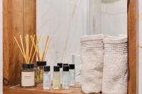 a shelf with three bottles of essential oils and towels at Luxury Cocon by Les Maisons de Charloc Homes in Boulogne-Billancourt