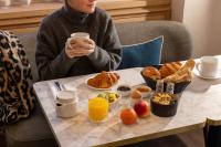 a woman sitting at a table with a tray of breakfast foods at Bijou Hôtel Paris Boulogne in Boulogne-Billancourt