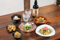 a table with bowls of food and a bottle of beer at LAMP Iki in Iki