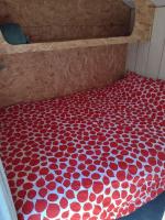 a bed with a red and white comforter on it at En attendant que ça pousse avec bain nordique privatif in Theix