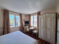 a bedroom with a bed and a table and windows at Hotel Villa Catarie in Guéthary
