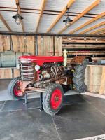an old red tractor parked in a barn at Camping Fuussekaul in Heiderscheid