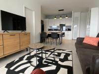 a living room with a couch and a tv and a table at Bel appartement avec vue sur la Baie d&#39;Authie in Berck-sur-Mer