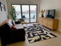 a living room with a couch and a tv and a table at Bel appartement avec vue sur la Baie d&#39;Authie in Berck-sur-Mer