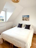 a bedroom with a large bed with white sheets and pillows at Charmante maison familiale in Ouistreham
