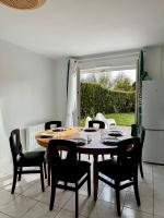 a dining room with a table and black chairs at Charmante maison familiale in Ouistreham