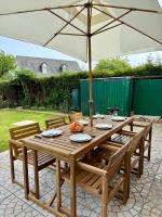 a wooden table with an umbrella on a patio at Charmante maison familiale in Ouistreham
