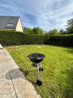 a barbecue grill in the grass in a yard at Charmante maison familiale in Ouistreham