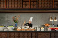 a chef standing in a kitchen preparing food at Wyndham Hoi An Royal Beachfront Resort & Villas in Hoi An