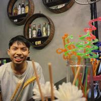 a young man is smiling next to a counter with drinks at Vi TamCoc Hotel in Ninh Binh