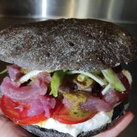 une personne tenant un sandwich avec de la viande et des légumes dans l'établissement Paso a Paso, à Terlizzi