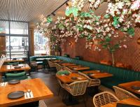 ein Restaurant mit Holztischen und Blumen an der Wand in der Unterkunft FD Hotels in Rotterdam