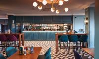 un ristorante con tavoli e sedie e un bar di Thistle London Heathrow Terminal 5 a Hillingdon