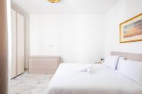 a white bedroom with a bed and a dresser at Msida Central Suites in Msida