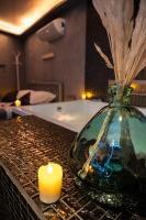 a candle and a vase on a table with a bath tub at Suite Romantique in Narbonne