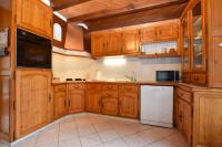 a kitchen with wooden cabinets and a white refrigerator at « La tranquillité » Villa avec piscine in Saint-Hilaire-de-Riez