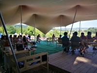 a group of people sitting at tables under a tent at Glamp-Inn Kapolcs in Kapolcs