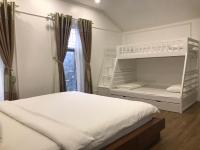 ein Schlafzimmer mit einem weißen Etagenbett und einem Fenster in der Unterkunft Biệt Thự Lan Anh Đà Lạt in Da Lat