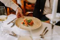 a person holding a plate of food on a table at Hotel Auszeit St Lambrecht in Sankt Lambrecht