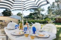 a table with white chairs and an umbrella at La villa Laurette - Maison de vacances familiale in Île dʼAix