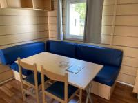 a dining room with a blue couch and a table at Bungalow pour 5 - TV - Clim - Terrasse ensoleillée in Boofzheim