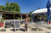 a woman standing next to a chalkboard in front of a restaurant at Bungalow pour 5 - TV - Clim - Terrasse ensoleillée in Boofzheim